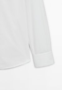 Long-sleeve white dress shirt with a single-button cuff and a curved hem on a flat, white background.
