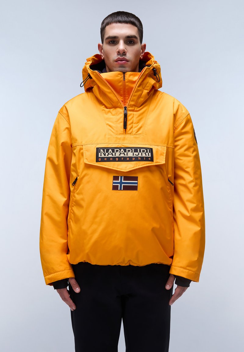 Pomarańczowa, ocieplana kurtka z wysokim kołnierzem, przednią kieszenią i logo "Napapijri". Posiada czarno-białą naszywkę z flagą.