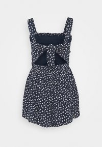 Mörkblå klänning med vitt blommönster, smockat liv, fyrkantig halsringning och knytning vid midjan. Designad med breda axelband.