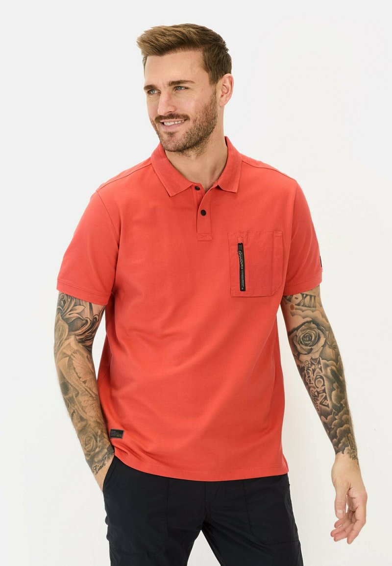 Rode polo-shirt van gladde stof, met een kraag, korte mouwen en een ritszak op de borst. Aangevuld met een zwart etiket.