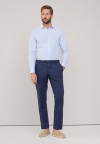 Himmelblau- und weißgestreiftes Hemd mit Knöpfen, marineblaue Hose und beige Slip-On-Schuhe. Minimalistisches Design, figurschnittige Form, glatte Textur.