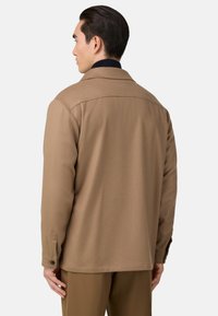 Brun ullblandad jacka med en strukturerad krage, knäppta ärmavslut och en ryggsömn. Slät textur med något skräddarsydd passform.