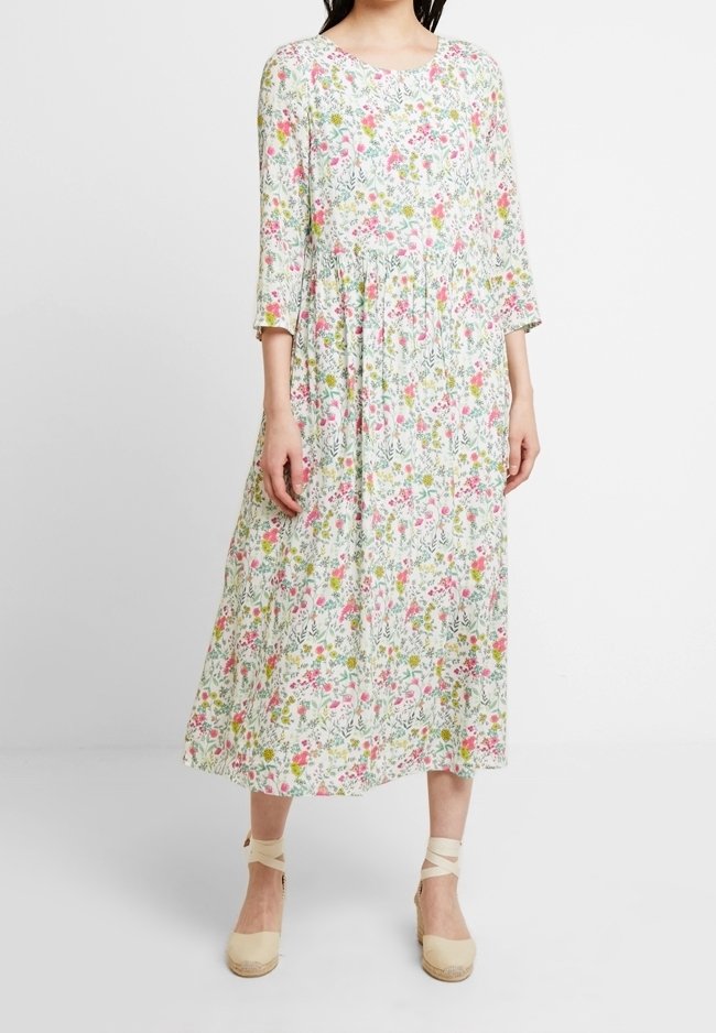Robe midi florale à manches 3/4, avec une base blanche, des motifs roses et verts, un col rond et un tissu froncé à la taille.