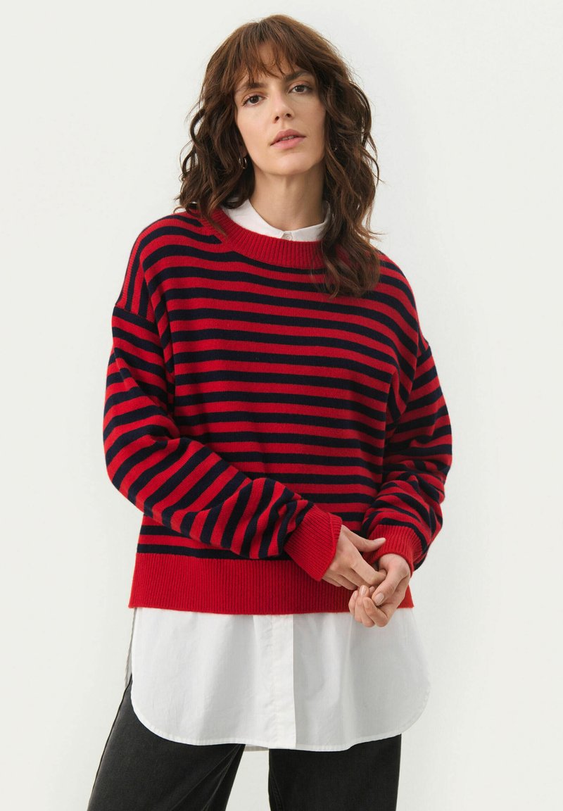 Rood en marineblauw gestreepte trui met een geribde halslijn en manchetten, gedragen over een witte blouse met kraag, met een ontspannen pasvorm en een zachte textuur.