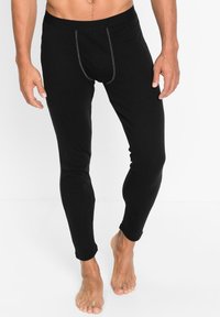 Schwarze Leggings aus dehnbarem Material, mit einer figurschmeichelnden Passform, elastischem Bund und kontrastierenden Besätzen entlang der vorderen Naht.