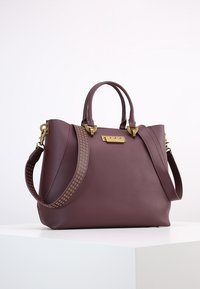 Borsa a mano in pelle bordeaux con hardware dorato, doppi manici e una tracolla perforata. Presenta una forma strutturata e una texture liscia.