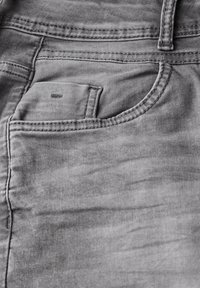 Tejido de mezclilla gris con un bolsillo principal con costuras visibles y un pequeño bolsillo adicional en la parte superior, textura suave con un sombreado sutil.