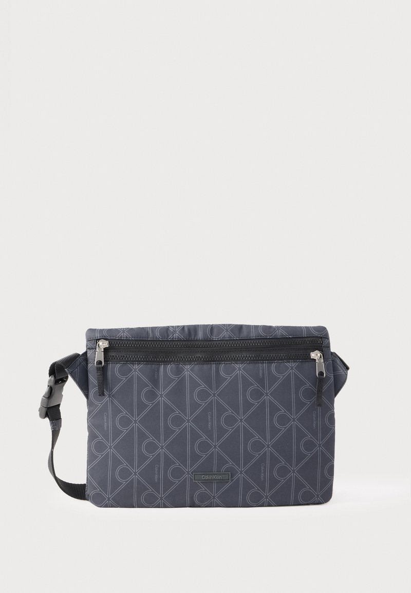 Ciemnoszara nerka Calvin Klein z geometrycznym wzorem, przednią kieszenią na zamek i regulowanym paskiem z klamrą.