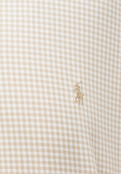 Bež i bijelo karirano platno s malim izvezenim logotipom bež polo igrača na desnoj strani.