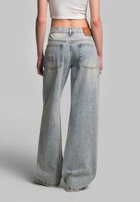 Wide-leg jeans in light blue denim with a faded texture. Features two back pockets and a brown leather brand patch on the waistband.