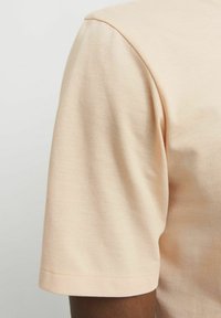 Licht perzik kleurig T-shirt met korte mouwen, gemaakt van soepel katoen, met een ronde halslijn en een eenvoudige, nette zoom zonder verdere details.