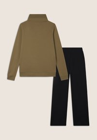 Top de manga larga verde oliva con cuello alto, combinado con pantalones negros. Ambos artículos tienen una textura suave y un ajuste relajado.