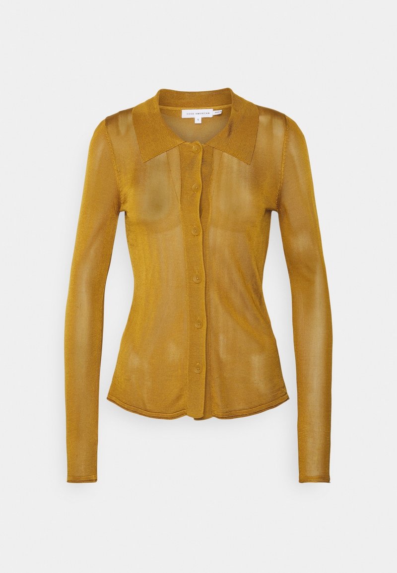 Långärmad skjorta i senapsgul med knappar, mjuk ribbad textur, figursydd passform och spetsig krage. Fem knappar framtill.