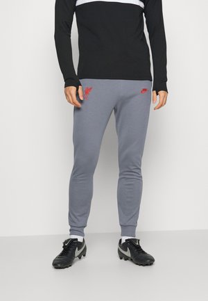 Pantalons de sport gris avec des poignets élastiques, arborant le logo de Liverpool FC en rouge ainsi qu'un petit logo Nike. Fabriqués en tissu doux et extensible.