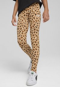 Leggingi s tkanino z leopardjim vzorcem v rjavih tonih, prilegajoče zasnove, raztegljiv material. Bel logotip Puma na stegnu, v kombinaciji z belimi športnimi copati.