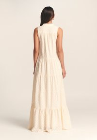 Vestito maxi lungo e a strati in bianco sporco con un sottile motivo testurizzato, design senza maniche e colletto sul retro.