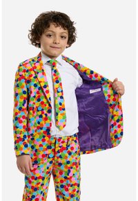 Completo a pois colorati in rosa, verde, giallo, blu e rosso, con una fodera viola. Include cravatta coordinata e dettagli con bottoni.