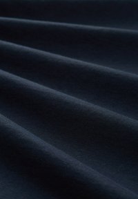 Ciemnonawowa tkanina o gładkiej fakturze, z miękkimi, falistymi konturami i subtelnym połyskiem na powierzchni, co wskazuje na elastyczność i drapowanie.