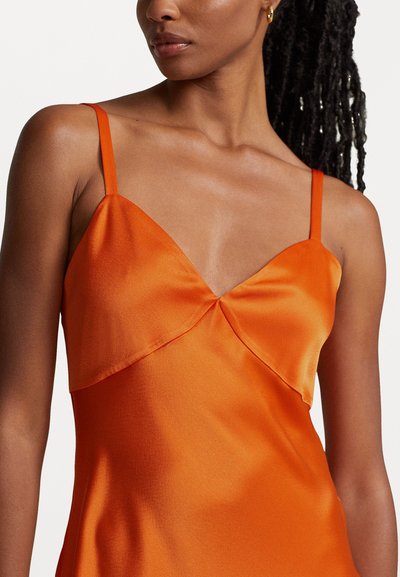 Robe en satin orange avec des bretelles fines réglables et un décolleté en V superposé, présentant une texture lisse et brillante.