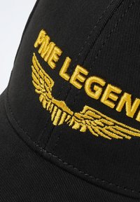 Casquette noire avec broderie jaune "PME LEGEND" et design d'aile. Fabriquée en tissu, avec une forme structurée et une visière courbée.