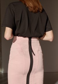 Black short-sleeve t-shirt paired with a high-waisted pink skirt featuring a central black zipper and visible seam details.