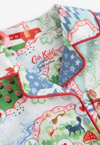 Flanell yö överalls set med en blandning av färgglada mönster, inklusive djur, träd och blommor, med röda detaljer och knappstängning.
