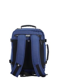 Mochila azul marino con correas de hombro acolchadas y ajustables, y un exterior de tela resistente. Presenta un asa en la parte superior y múltiples compartimentos con cremallera.