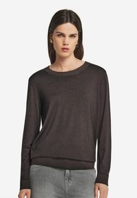 Mörkbrun långärmad tröja med rund halsringning och ribbade detaljer vid ärmsluten och nederkant, tillverkad av ett mjukt och smooth material.