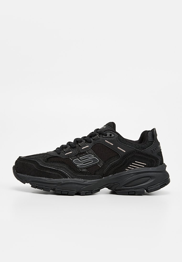 Chaussures de sport noires en mélange de maille et de matériaux synthétiques. Dotées d'une semelle épaisse, d'un bout arrondi et de accents métalliques subtils.