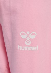 Rosa sweatshirt med en mjuk textur som har en vit logotyp av en bi och varumärket "hummel" tryckt under.