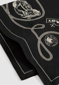 Tissu noir avec des motifs de corde blanche, graphique de crâne, emblème circulaire et texte partiel du logo "Levi's".