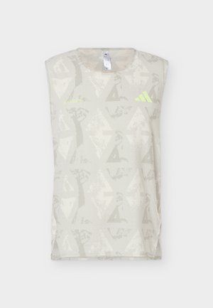 Débardeur de sport beige clair avec des motifs géométriques et abstraits subtils, petit texte jaune "LASRUM" et logo Adidas jaune sur le devant.