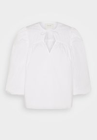 Blusa bianca con uno yoke trapuntato texture, scollo a fascia e maniche a sbuffo. Tessuto leggero, vestibilità ampia e orlo dritto.