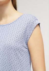 Ljusblå t-shirt med korta ärmar, prydd med ett prickmönster i svart. Mjuk tygkvalitet och rundad halsringning.