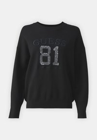 Svart sweatshirt med "GUESS" och "81" i silverpaljetter, rund halsringning, långa ärmar samt ribbad nederkant och ärmslut.