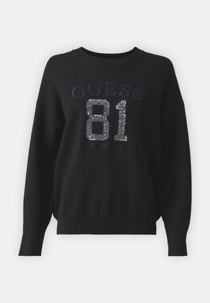 Svart sweatshirt med "GUESS" og "81" i sølvpaljetter, rund hals, lange ermer, og ribbestrikket linning og mansjetter.