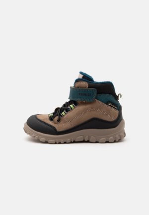 Chaussure de randonnée enfant marron et noire avec des accents verts, bride velcro marquée Primigi et semelle beige robuste, vue de côté sur fond blanc.