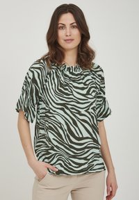 Top a maniche corte in morbido tessuto con un motivo a strisce zebra verdi e blu. Il collo è arricciato, con una vestibilità comoda e orlo curvo.