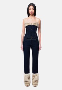 Denim jumpsuit with a structured bodice, fur trim at the neckline, and fur accents at the ankles. Dark blue color with gold buttons.