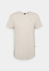 Beige bavlněné tričko s krátkým rukávem a kulatým výstřihem. Má malé logo na hrudi a boží štítek. Jednoduchý, ležérní design.