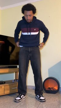 Marineblauer Hoodie mit bordeauxfarbenen und weißen Streifen, dunkle Denim-Jeans und schwarz-weiße Sneaker. Sanfte Textur und lässige Passform.