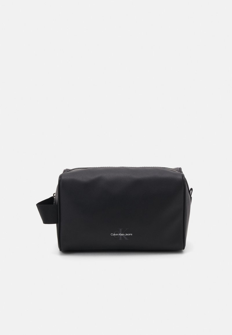 Bolsa de cosméticos preta feita de material suave e durável. Formato retangular com fecho de zíper e pega lateral. Apresenta um logótipo na frente.