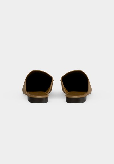 Paire de chaussures plates marron à enfiler, vues de dos sur un fond clair uni.