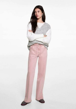 Ljust rosa högmidjade jeans med rak passform, strukturerad grå stickad väst över en vit långärmad skjorta, bärs med svarta slip-on skor.