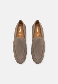 Des chaussures slip-on en daim gris avec une surface lisse, des accents cousus et un design à bout rond. La semelle intérieure présente un texte de marque en relief.