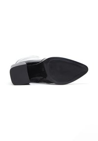 Chaussure en cuir verni noir avec un bout pointu et un petit talon carré. Semelle en caoutchouc texturée avec de légers grooves pour une meilleure adhérence. Taille 36 marquée à l'intérieur.