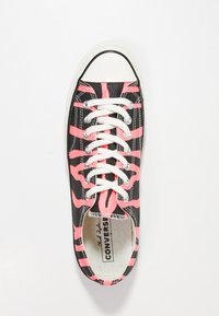 Svart kanvas sneakers med rosa abstrakt mönster, vita snörningar, gummitåhätta och klassisk Converse-logga på innersulan.