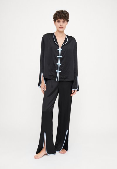 Sort satin pyjamassæt med en langærmet skjorte med blå piping og knaplukninger, parret med flagrende bukser med sideslids.