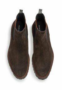 Stivaletti alla caviglia in suede marrone con pannelli elastici laterali, punta arrotondata e dettagli arancioni a contrasto. Suola in gomma con battistrada per una migliore aderenza.