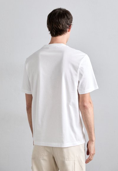 Witte katoenen t-shirt met korte mouwen en een ronde hals, zonder versieringen, weergegeven van de achterkant op een model tegen een neutrale achtergrond.
